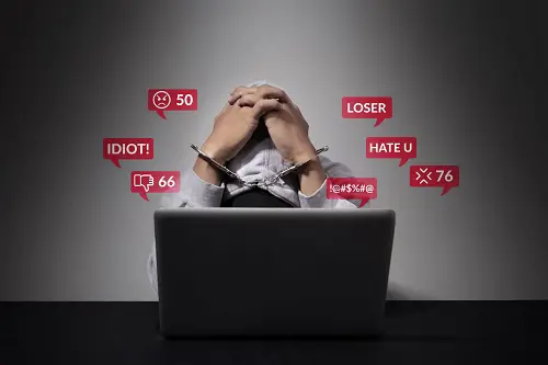 une personne devant son ordinateur , effondrée en lisant  des commentaires sur internet comme "idiot", loser"  etc..