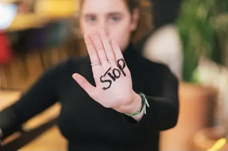 une femme avance la paume de sa main avec le mot "stop"