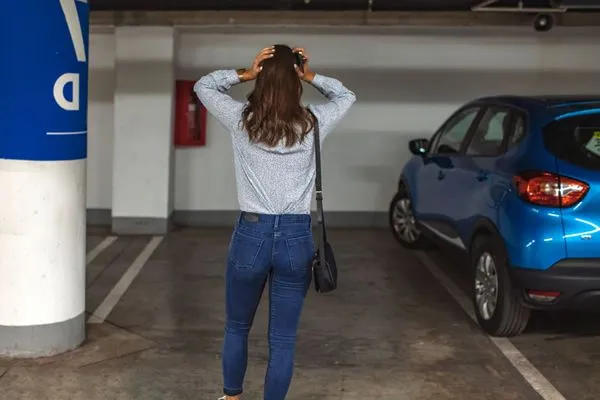 une femme prend sa tête dans ses mains en découvrant que sa voiture a été volée dans un parking